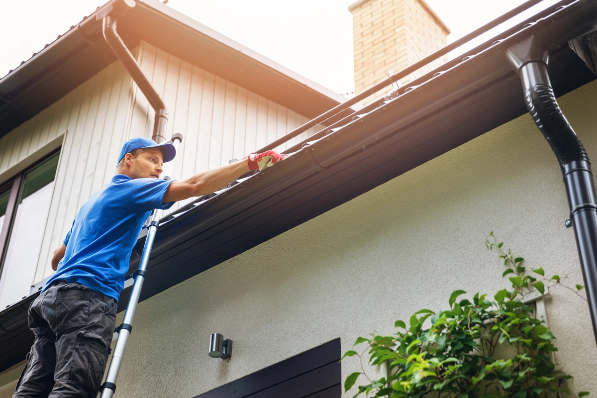 hi fi image of a roof tech on ladder cleaning gutters
