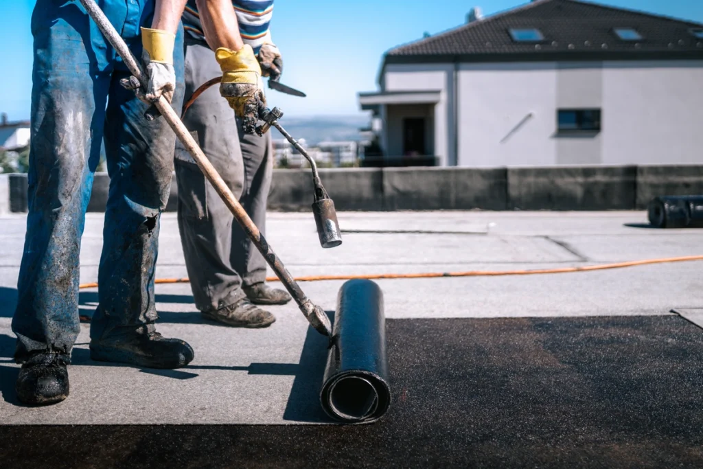 roof techs working on flat roof of home