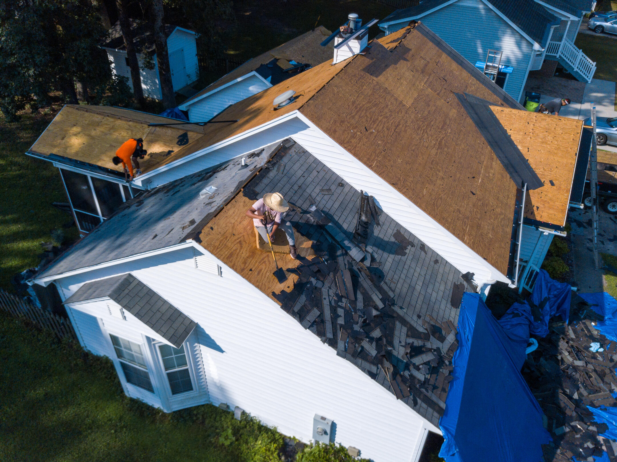 how to get insurance to pay for roof replacement-arial view of team of roofers removing old roofing