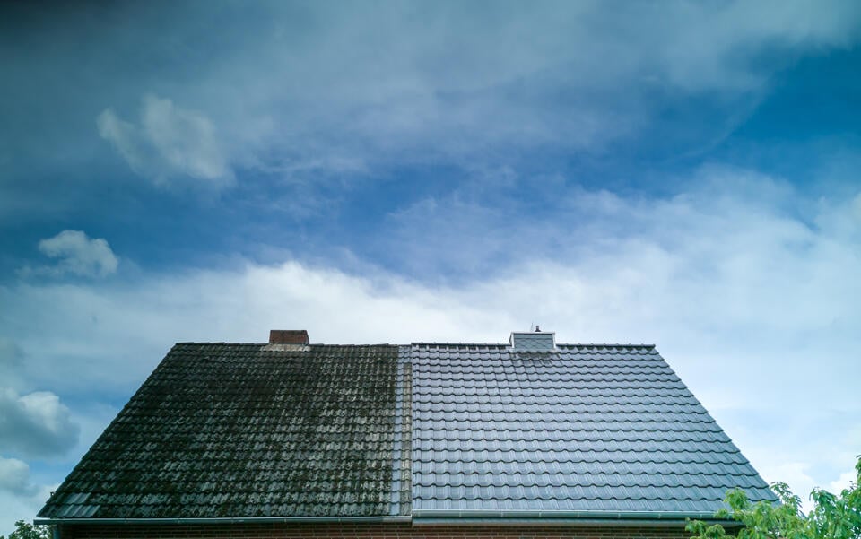 roof washing-tiled roof under cloudy sky with the right have just cleaned and the left have filthy