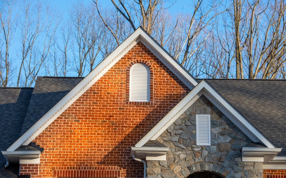 soffit vents-brick and stone sided house with white soffits and gray shingle roof